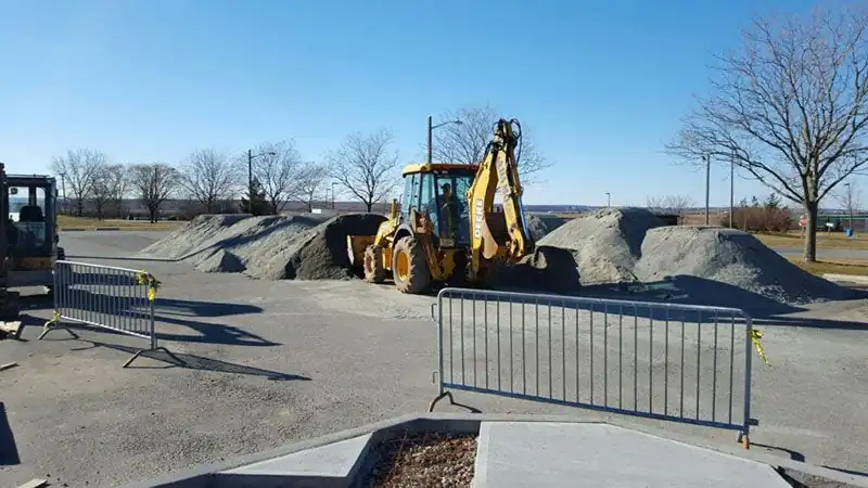 Adamo Bros branded backhoe loader working on a jobsite with graded gravel