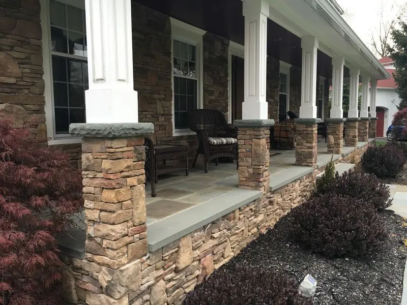 Long stacked stone porch with columns and bluestone caps built by Adamo Brothers Construction
