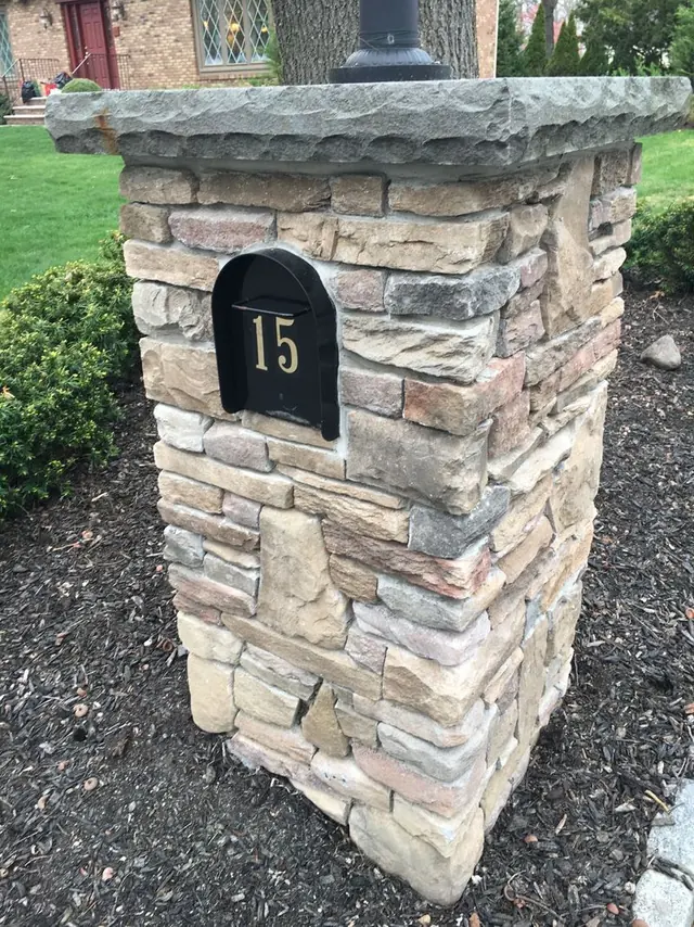 Stacked stone mailbox and lamp pillar with a bluestone cap in front of a Bergen County home